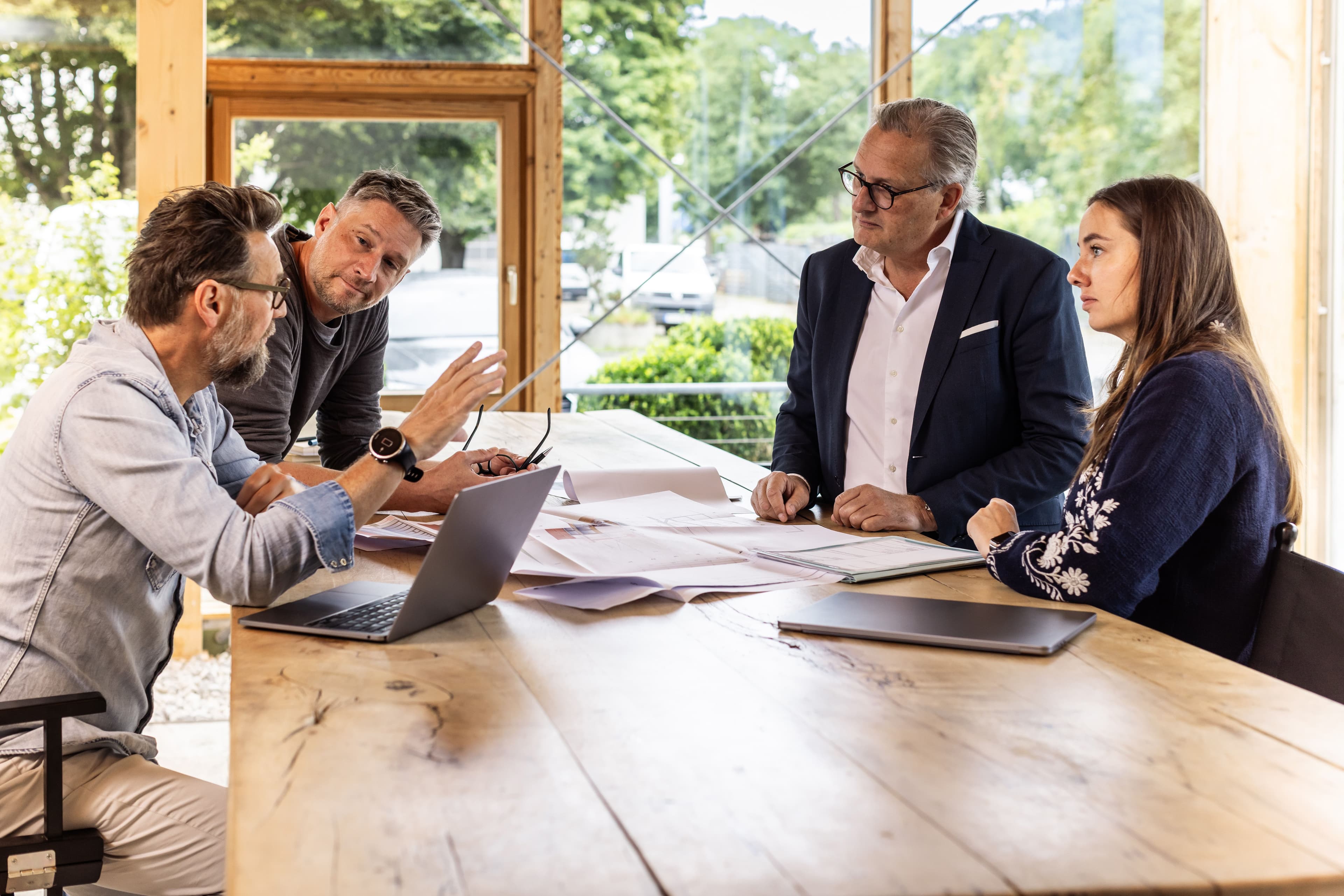 3lectrify team collaborating in a modern meeting room, discussing strategy around a wooden conference table with laptop and documents
